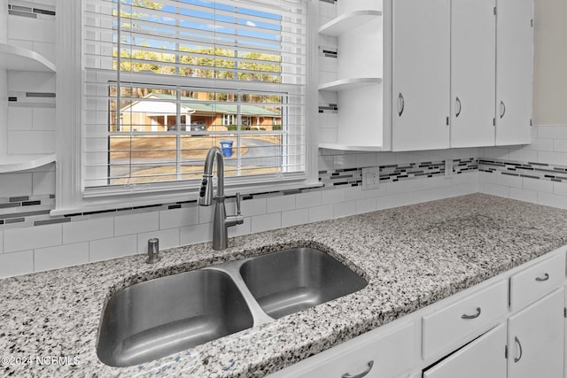 kitchen featuring white cabinets, tasteful backsplash, sink, and light stone counters