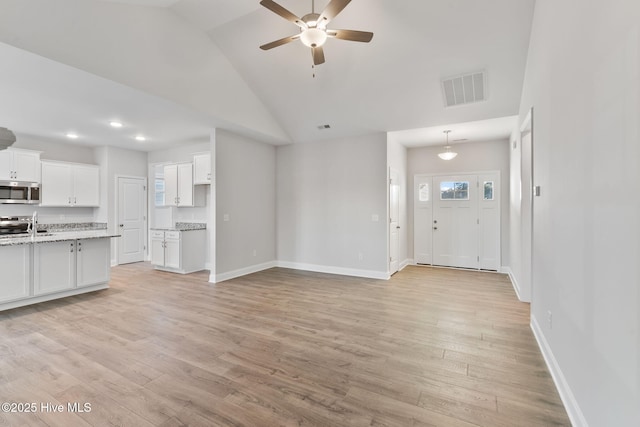 unfurnished living room with light wood-type flooring, baseboards, visible vents, and ceiling fan