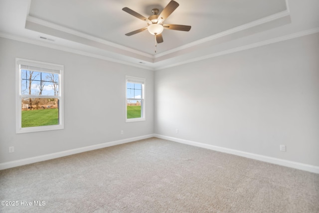 carpeted empty room featuring crown molding, a raised ceiling, and baseboards