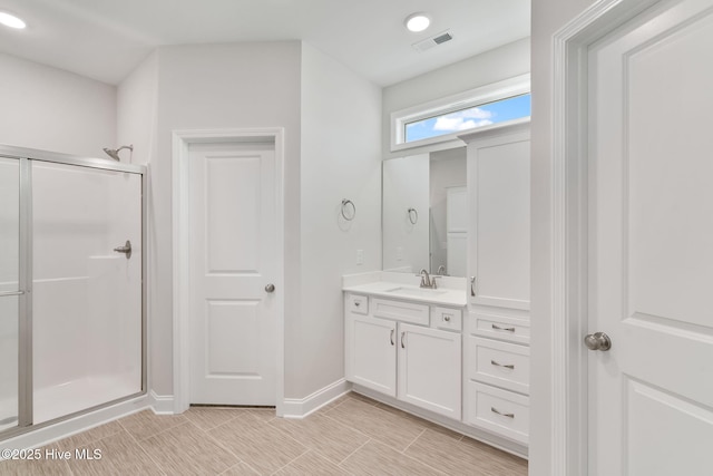 bathroom featuring vanity, a shower stall, visible vents, and baseboards