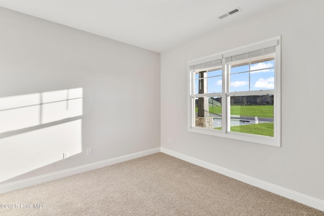 empty room with carpet floors, baseboards, and visible vents