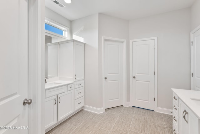 bathroom with vanity, visible vents, and baseboards