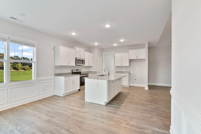 kitchen with appliances with stainless steel finishes, white cabinets, visible vents, and a sink