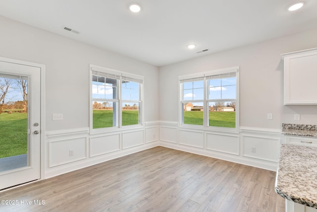 unfurnished dining area with light wood finished floors, wainscoting, visible vents, and recessed lighting