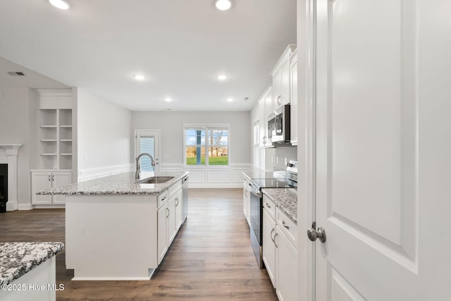 kitchen with stainless steel appliances, a fireplace, a sink, visible vents, and built in features