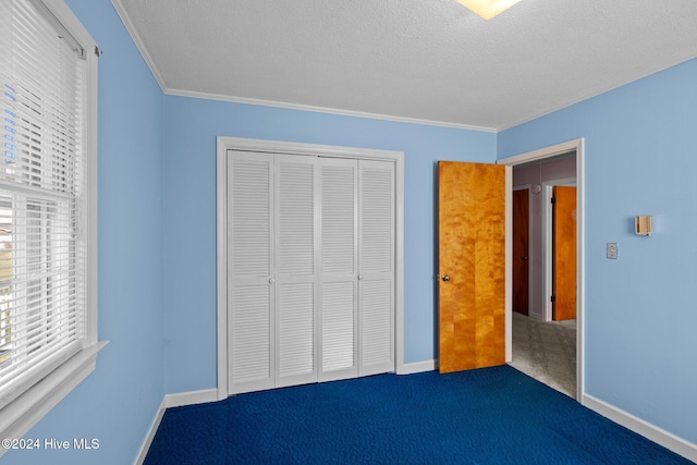 unfurnished bedroom featuring a closet, ornamental molding, a textured ceiling, and dark colored carpet