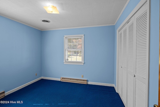 unfurnished bedroom with ornamental molding, a closet, a baseboard heating unit, and carpet flooring