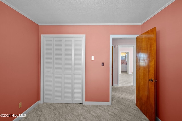 unfurnished bedroom with a closet, a textured ceiling, ornamental molding, and light colored carpet