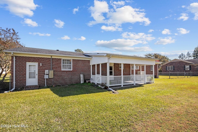 back of property featuring covered porch and a lawn