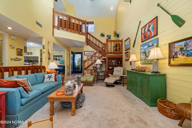 carpeted living room featuring a healthy amount of sunlight, a towering ceiling, and wood walls