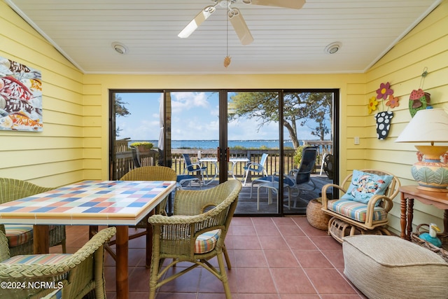 sunroom / solarium featuring wood walls, tile patterned flooring, a ceiling fan, and outdoor dining area