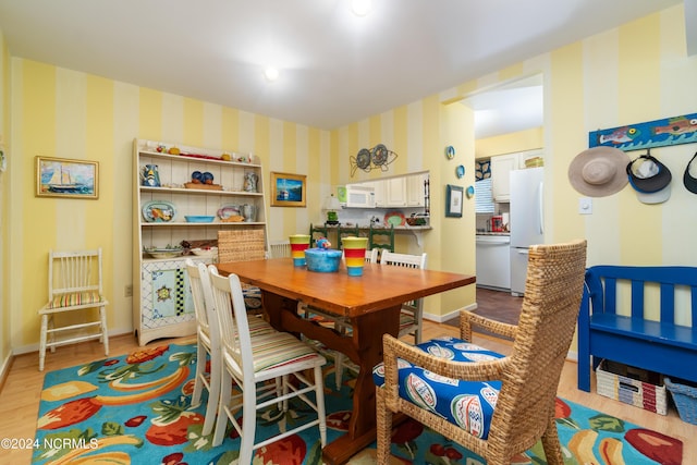 dining area featuring baseboards, light wood finished floors, and wallpapered walls