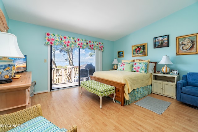 bedroom featuring access to outside, lofted ceiling, and light wood-type flooring