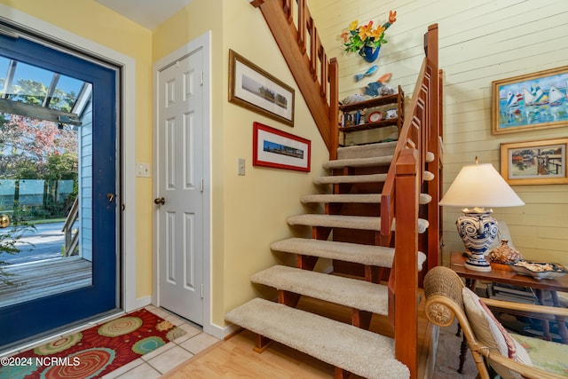 stairs with wooden walls and tile patterned flooring