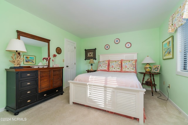 bedroom with baseboards and light colored carpet
