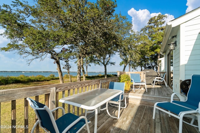 deck with a water view and outdoor dining space