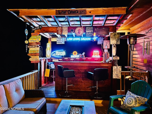 bar featuring hardwood / wood-style floors and wooden walls