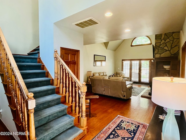 stairs with lofted ceiling, french doors, and wood-type flooring