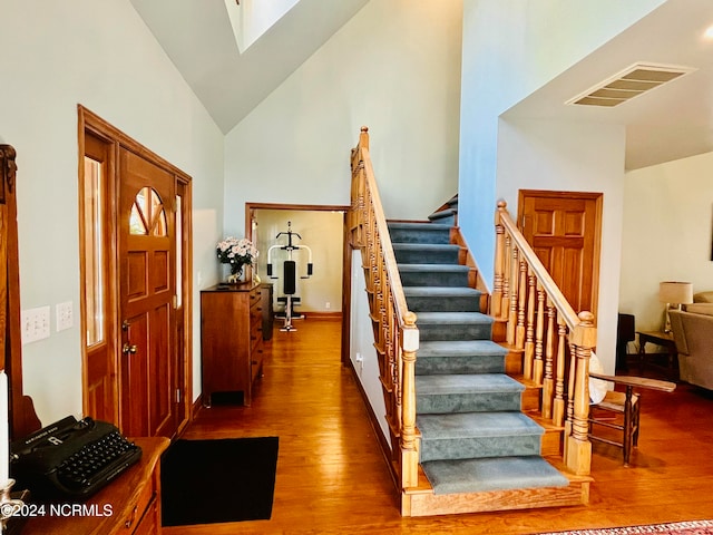 staircase featuring hardwood / wood-style floors and high vaulted ceiling