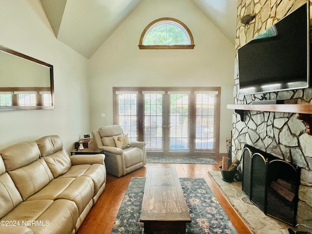 living room with light hardwood / wood-style floors, a healthy amount of sunlight, and high vaulted ceiling