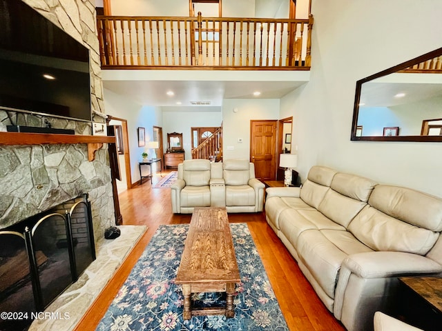 living room featuring a towering ceiling, a fireplace, and hardwood / wood-style floors