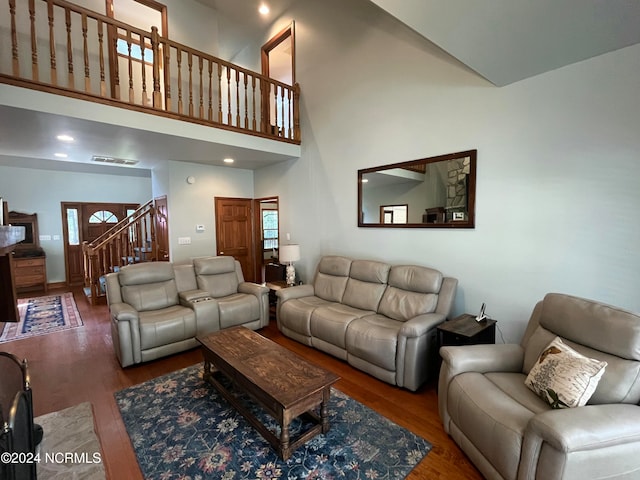 living room with a wealth of natural light, a high ceiling, and dark hardwood / wood-style flooring