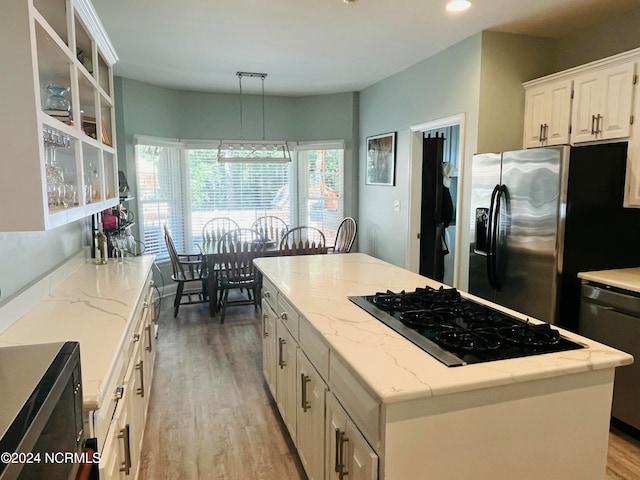 kitchen featuring appliances with stainless steel finishes, light hardwood / wood-style flooring, decorative light fixtures, and a center island