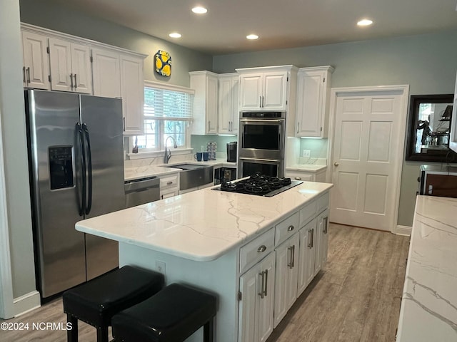 kitchen with white cabinetry, light hardwood / wood-style floors, stainless steel appliances, and sink