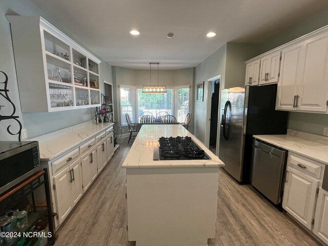 kitchen featuring white cabinetry, stainless steel appliances, light wood-type flooring, and a kitchen island