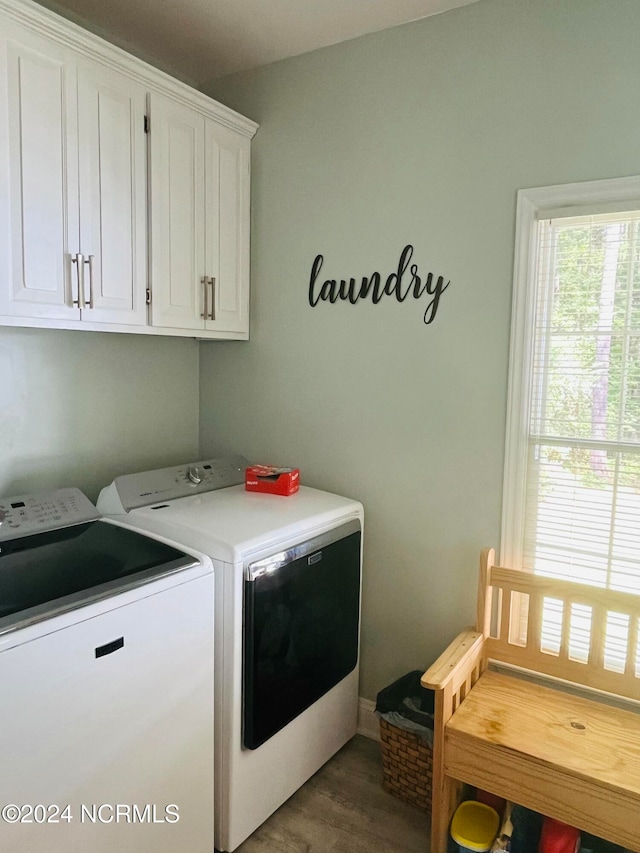 washroom with dark wood-type flooring, cabinets, and washer and clothes dryer