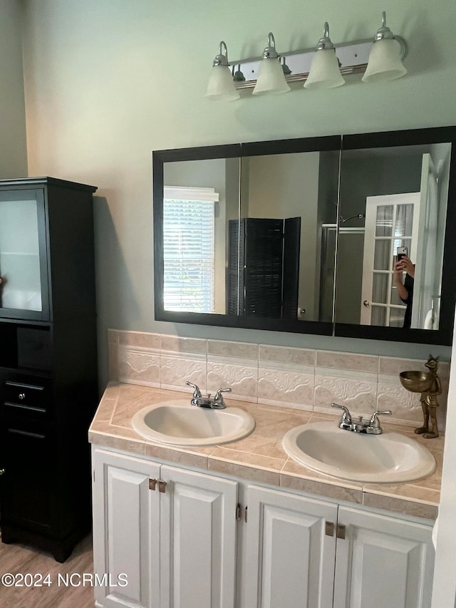 bathroom featuring vanity, hardwood / wood-style floors, tasteful backsplash, and an enclosed shower