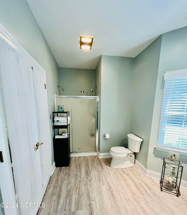 bathroom with a shower with door, toilet, and wood-type flooring