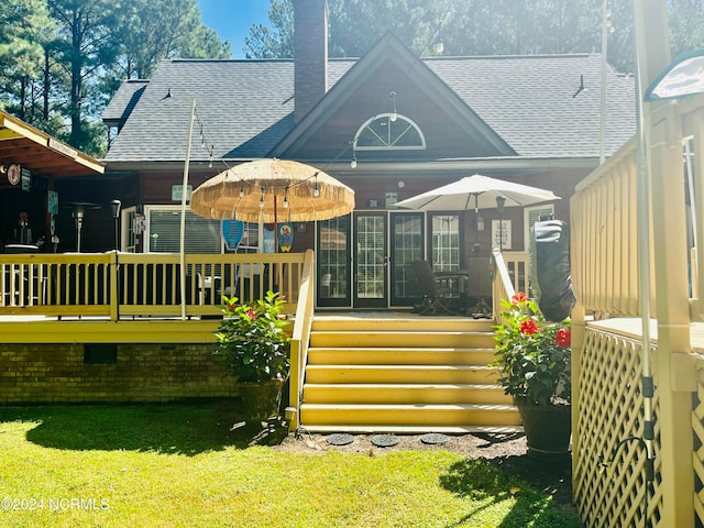 back of property with a wooden deck and a lawn