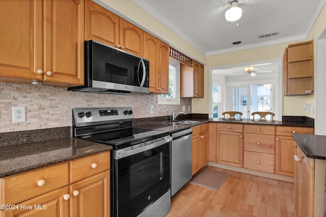 kitchen with stainless steel appliances, a sink, visible vents, dark stone counters, and crown molding