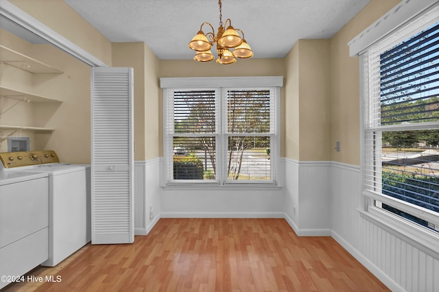 unfurnished dining area featuring a wainscoted wall, light wood-style flooring, a textured ceiling, and independent washer and dryer