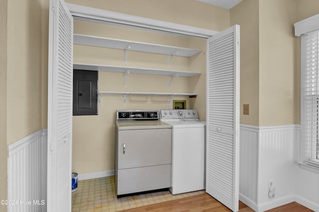 laundry room with laundry area, electric panel, a wainscoted wall, independent washer and dryer, and light floors