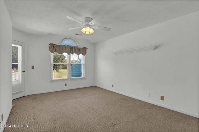 carpeted spare room featuring a ceiling fan, visible vents, a textured ceiling, and baseboards