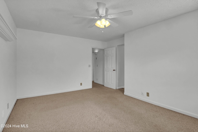 unfurnished bedroom featuring light carpet, a textured ceiling, a ceiling fan, and baseboards