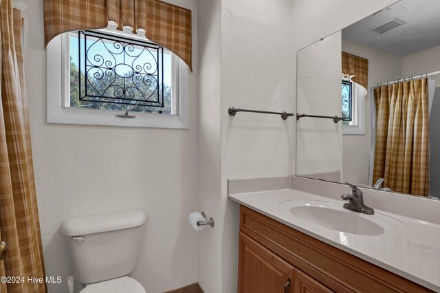 full bath with visible vents, vanity, and toilet