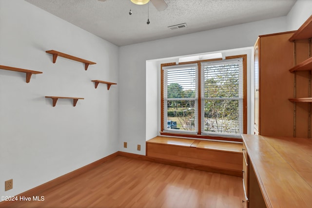 unfurnished dining area featuring a textured ceiling, ceiling fan, visible vents, baseboards, and light wood-type flooring