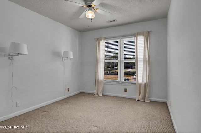 empty room with light carpet, ceiling fan, a textured ceiling, and baseboards