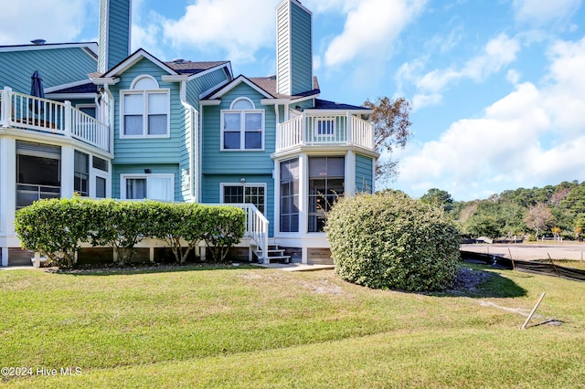 rear view of house featuring a chimney and a lawn