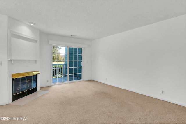 unfurnished living room with a fireplace with flush hearth, light colored carpet, a textured ceiling, and baseboards