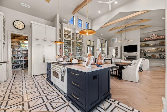 kitchen featuring high quality appliances, white cabinetry, decorative light fixtures, and a center island