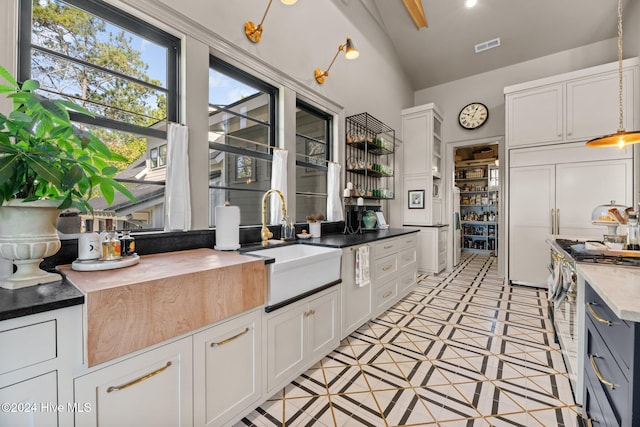 kitchen with white cabinetry, high vaulted ceiling, sink, and high end appliances