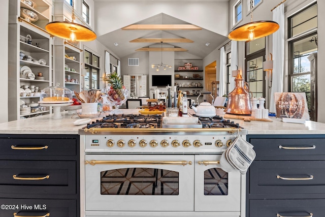 kitchen with lofted ceiling, light stone counters, decorative light fixtures, and high end white range