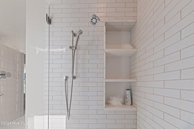 bathroom with brick wall and a tile shower