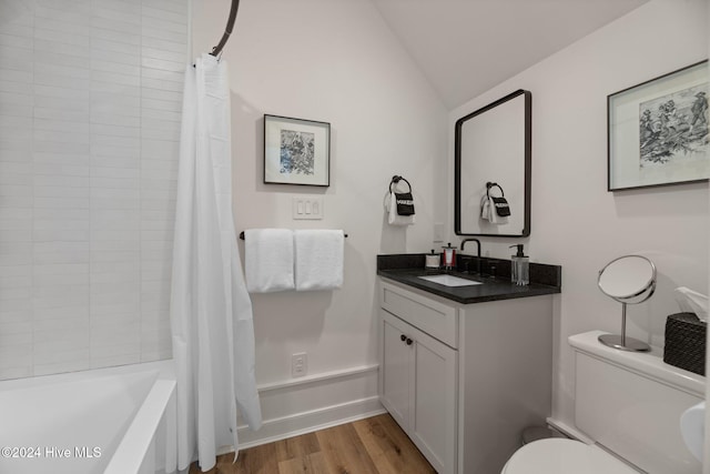 full bathroom with hardwood / wood-style flooring, toilet, vaulted ceiling, shower / tub combo with curtain, and vanity