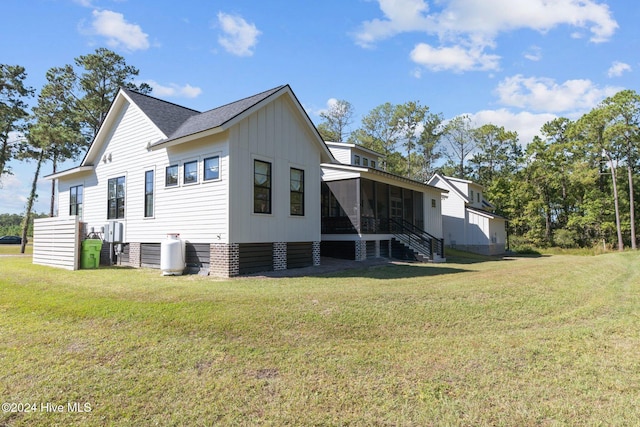 rear view of house with a sunroom and a lawn