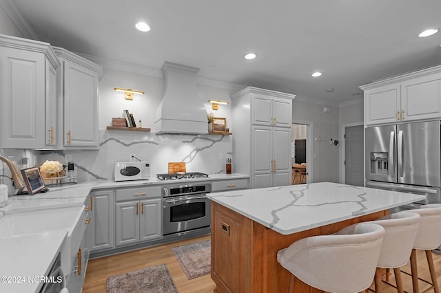 kitchen featuring a kitchen bar, premium range hood, stainless steel appliances, a kitchen island, and white cabinetry